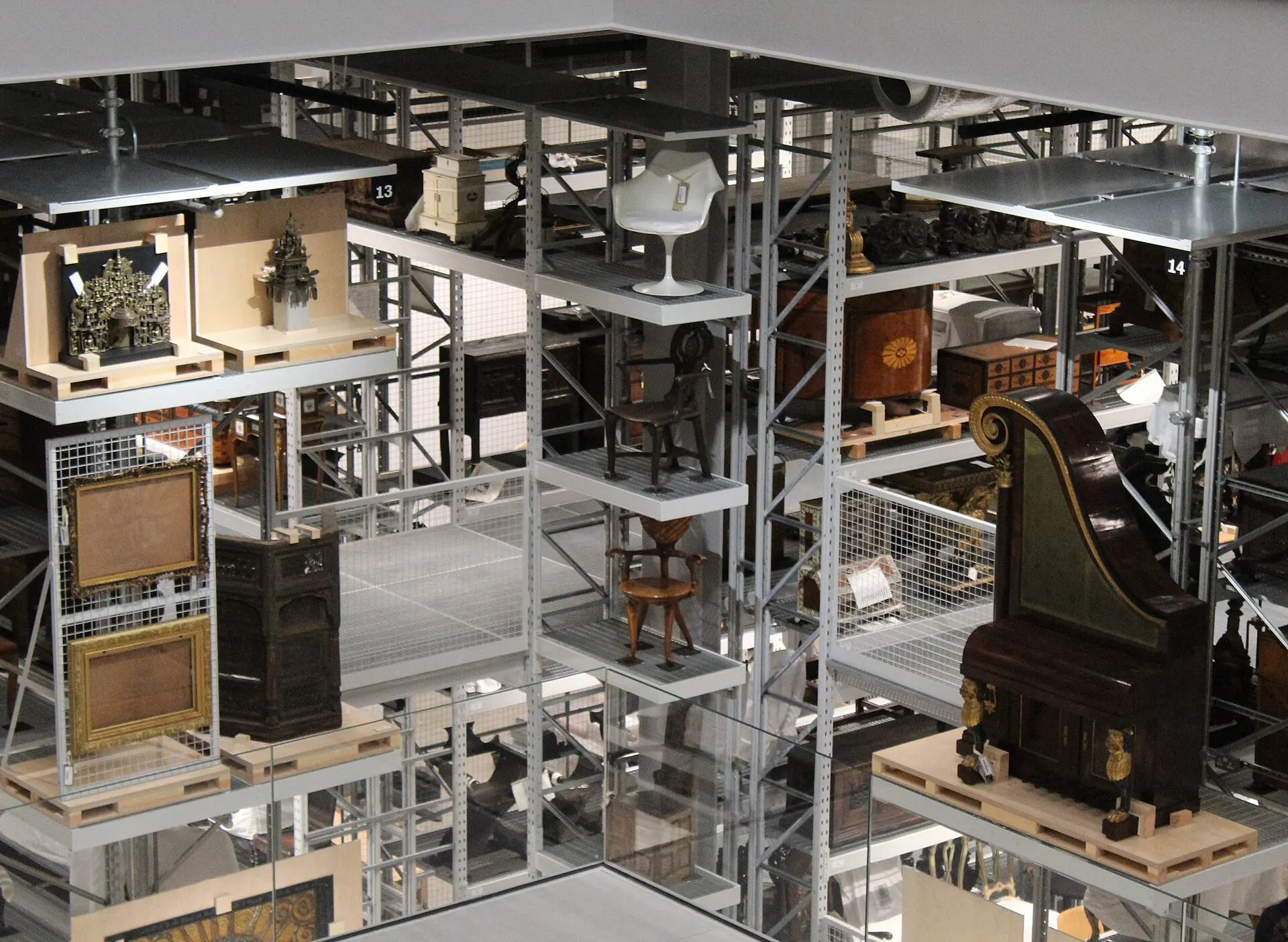 Tall storage racks holding furniture, frames and objects, each labeled with a tag